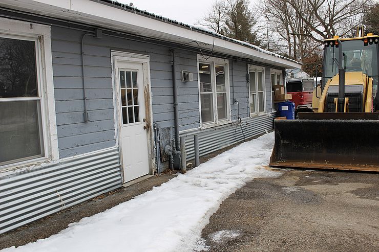 Blue Public Works Building with construction vehicle beside it.